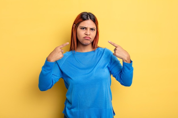 Jeune femme hispanique avec une mauvaise attitude à la recherche de fierté et d'agressivité pointant vers le haut ou faisant signe amusant avec les mains