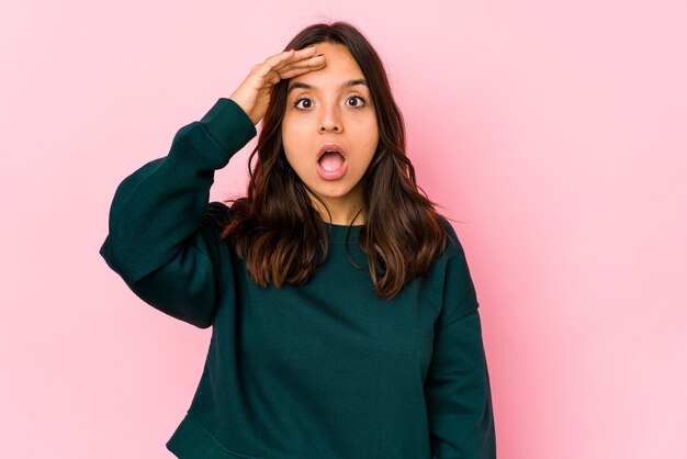 Jeune femme hispanique métisse crie fort, garde les yeux ouverts et les mains tendues.