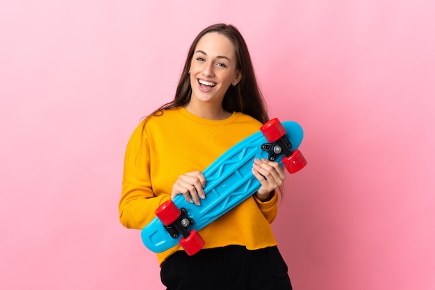 Jeune femme hispanique sur mur rose isolé avec un patin avec une expression heureuse