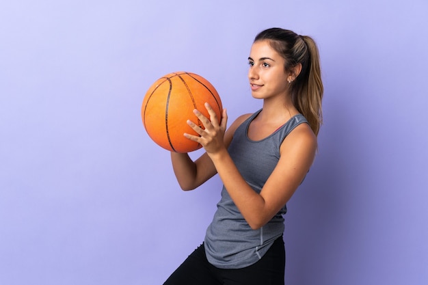 Jeune femme hispanique sur mur violet isolé jouant au basket