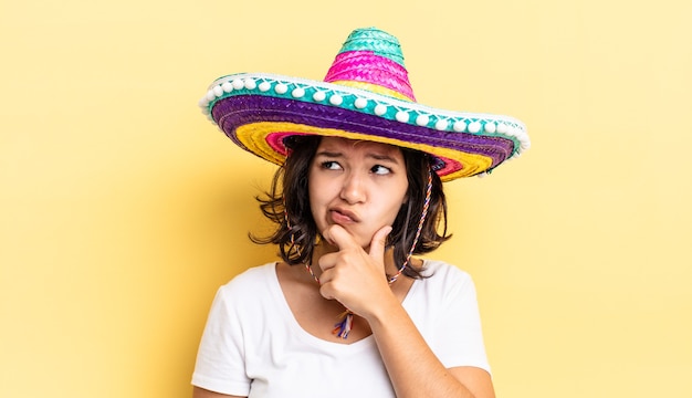 Jeune femme hispanique pensant, se sentant dubitative et confuse. concept de chapeau mexicain