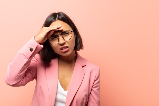 Jeune femme hispanique à la perplexité et étonné, avec la main sur le front à la recherche de loin, regarder ou chercher