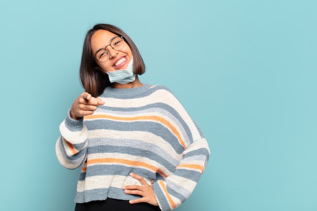 Jeune femme hispanique pointant vers l'avant avec un sourire satisfait, confiant et amical, vous choisissant