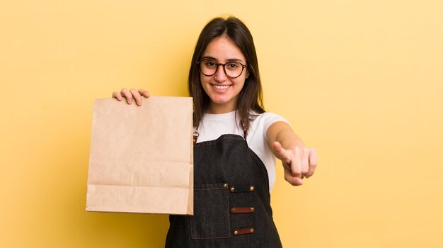 Jeune femme hispanique pointant vers la caméra en vous choisissant le concept de livraison de restauration rapide