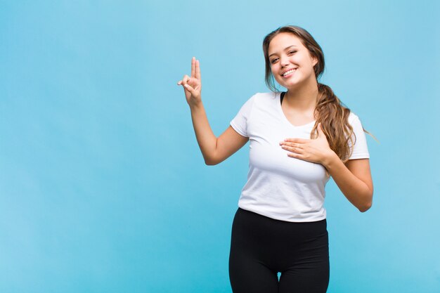 Jeune femme hispanique à la recherche de bonheur, confiant et digne de confiance, souriant et montrant le signe de la victoire, avec une attitude positive