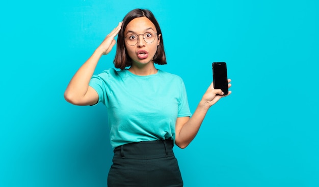 Jeune Femme Hispanique à La Recherche De Bonheur, étonné Et Surpris, Souriant Et Réalisant Une Bonne Nouvelle Incroyable Et Incroyable