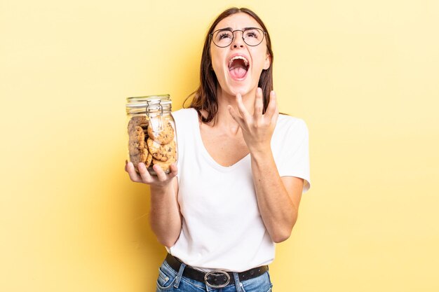 Jeune femme hispanique à la recherche désespérée de concept de bouteille de biscuits frustrés et stressés