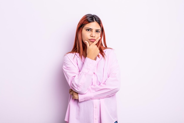 Jeune femme hispanique à la recherche sérieuse réfléchie et méfiante avec un bras croisé et la main sur les options de pondération du menton