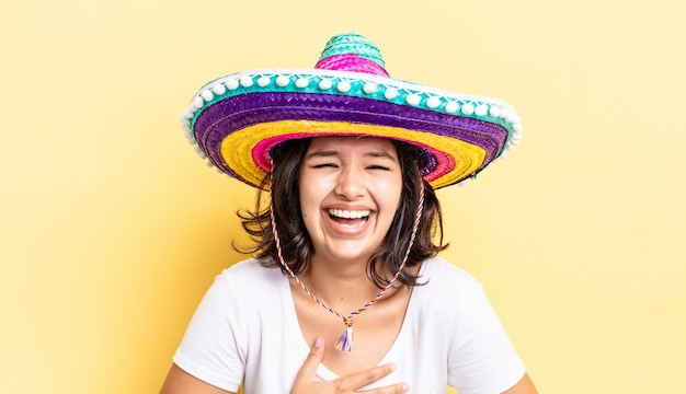 Jeune femme hispanique riant aux éclats d'une blague hilarante. concept de chapeau mexicain