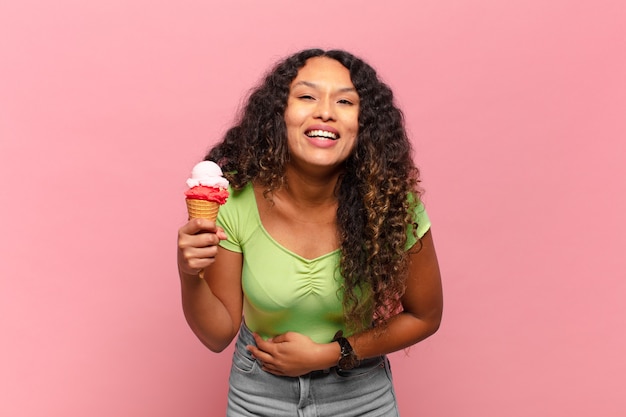 Jeune femme hispanique riant aux éclats d'une blague hilarante, se sentant heureuse et joyeuse, s'amusant. concept de crème glacée