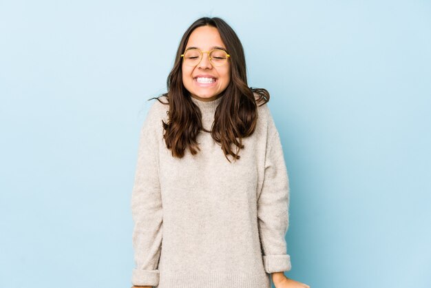 Jeune femme hispanique rit et ferme les yeux, se sent détendue et heureuse.