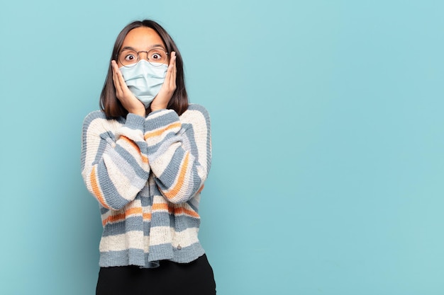 Jeune femme hispanique se sentant choquée et effrayée, l'air terrifiée avec la bouche ouverte et les mains sur les joues