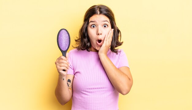 Jeune femme hispanique se sentant choquée et effrayée. concept de brosse à cheveux