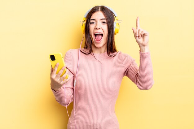 jeune femme hispanique se sentant comme un génie heureux et excité après avoir réalisé une idée. casque et concept de téléphone