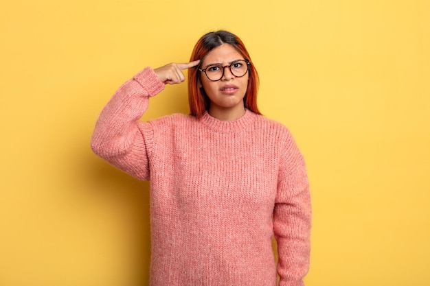 Jeune femme hispanique se sentant confuse et perplexe, montrant que vous êtes fou, fou ou fou