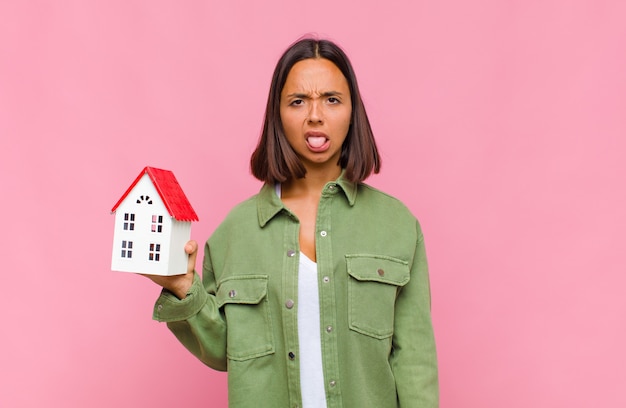 Jeune femme hispanique se sentant dégoûtée et irritée, tirant la langue, n'aimant pas quelque chose de méchant et dégueulasse