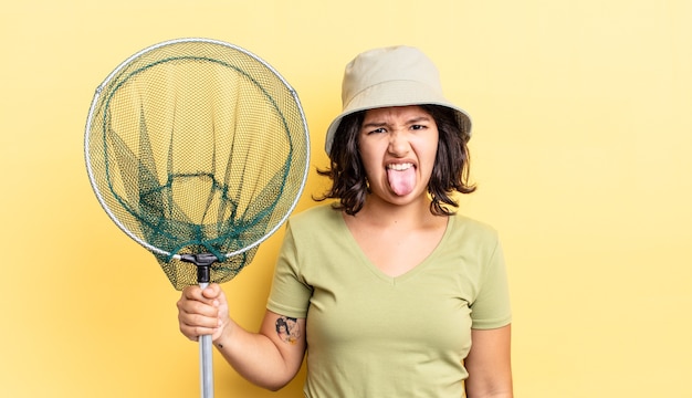 Photo jeune femme hispanique se sentant dégoûtée et irritée et tirer la langue. concept de filet de pêcheur