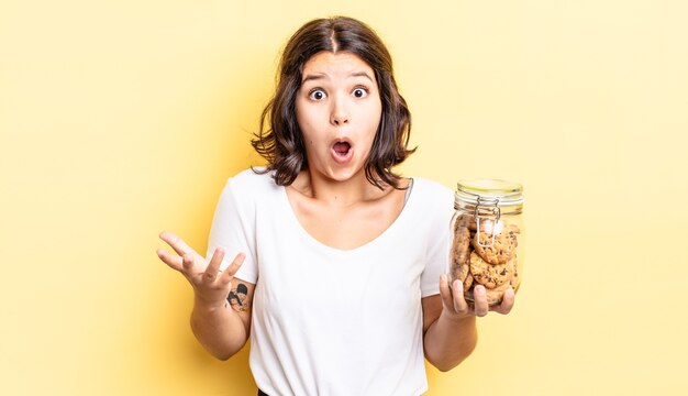 Jeune femme hispanique se sentant extrêmement choquée et surprise. concept de bouteille de biscuits