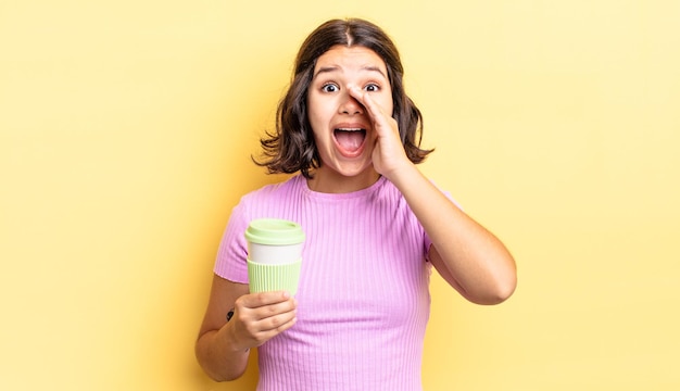 Jeune femme hispanique se sentant heureuse, donnant un grand cri avec les mains à côté de la bouche. concept de café à emporter