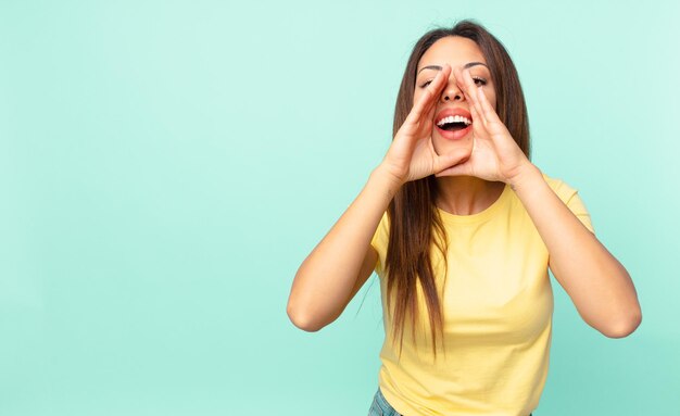 Jeune femme hispanique se sentant heureuse, donnant un grand cri avec les mains à côté de la bouche