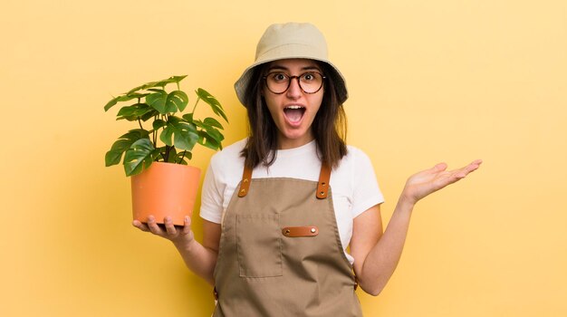 Jeune femme hispanique se sentant heureuse et étonnée de quelque chose d'incroyable concept de jardinier et de plante