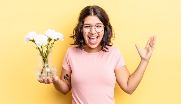 Jeune femme hispanique se sentant heureuse et étonnée de quelque chose d'incroyable. concept de pot de fleurs