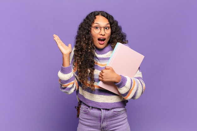 Jeune femme hispanique se sentant heureuse, excitée, surprise ou choquée, souriante et étonnée de quelque chose d'incroyable. étudiant