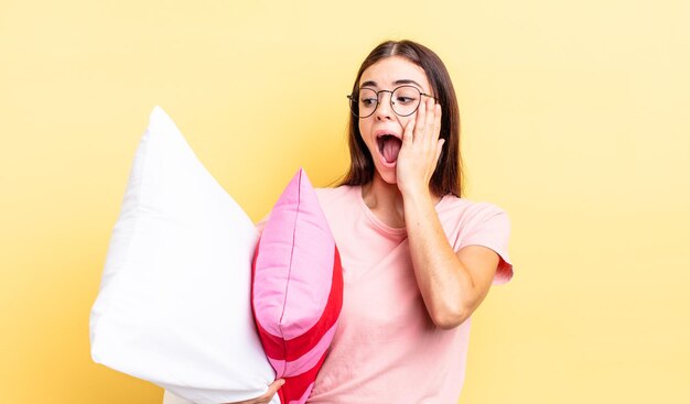 Jeune femme hispanique se sentant heureuse, excitée et surprise. concept de pyjama et d'oreiller