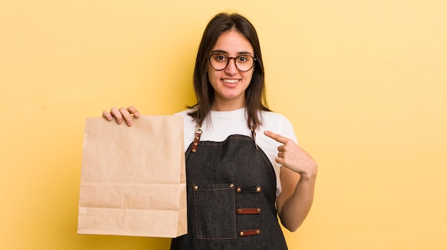Jeune femme hispanique se sentant heureuse et pointant vers soi avec un concept de livraison de restauration rapide excité