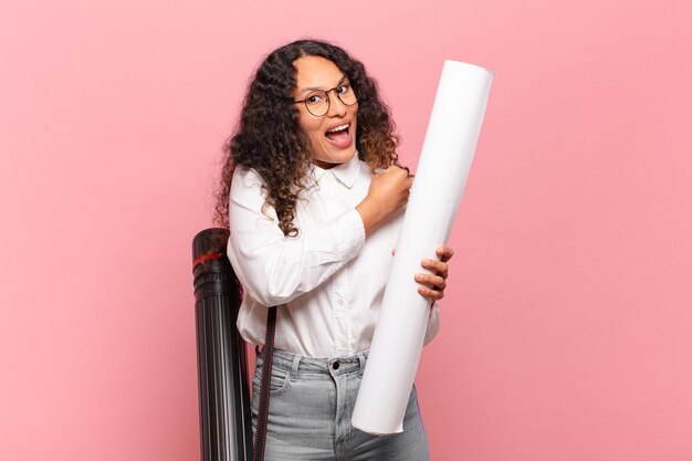 Jeune femme hispanique se sentant heureuse, positive et réussie, motivée face à un défi ou célébrant de bons résultats. concept d'architecte