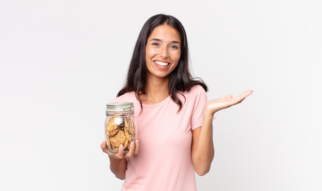 Jeune femme hispanique se sentant heureuse, surprise de réaliser une solution ou une idée et tenant une bouteille en verre de biscuits