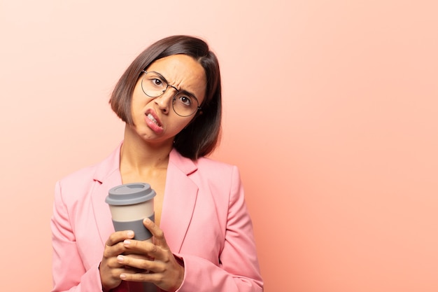 Jeune femme hispanique se sentant perplexe et confus, avec une expression stupide et stupéfaite en regardant quelque chose d'inattendu