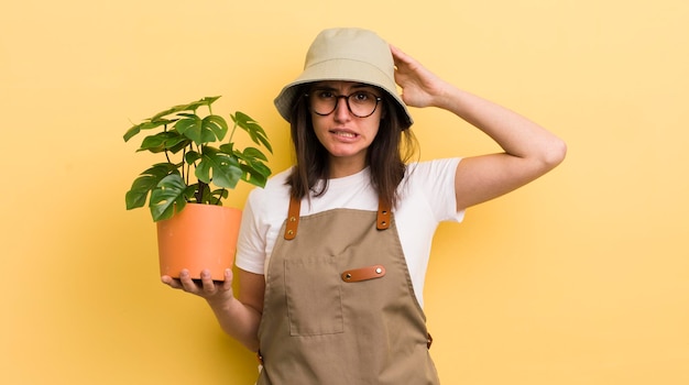 Jeune femme hispanique se sentant stressée anxieuse ou effrayée avec les mains sur la tête jardinier et concept de plante