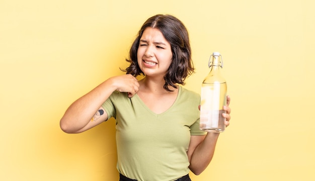 Jeune femme hispanique se sentant stressée, anxieuse, fatiguée et frustrée. concept de bouteille d'eau