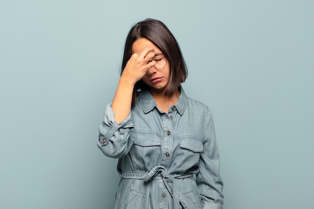 Jeune femme hispanique se sentant stressée, malheureuse et frustrée, touchant le front et souffrant de migraine de maux de tête sévères