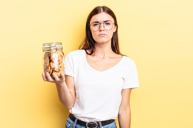 Jeune femme hispanique se sentant triste et geignarde avec un regard malheureux et un concept de bouteille de biscuits qui pleure