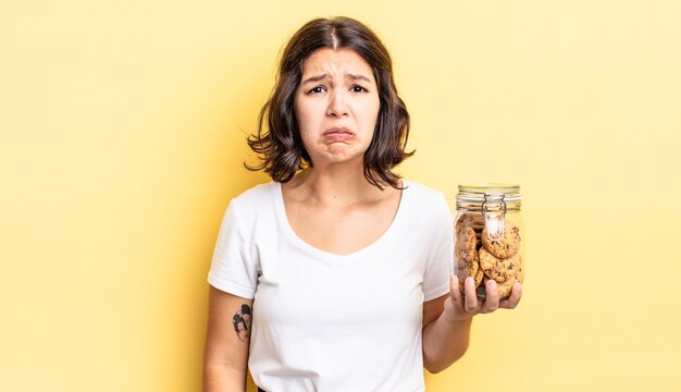 Jeune femme hispanique se sentant triste et pleurnicharde avec un regard malheureux et pleurant. concept de bouteille de biscuits