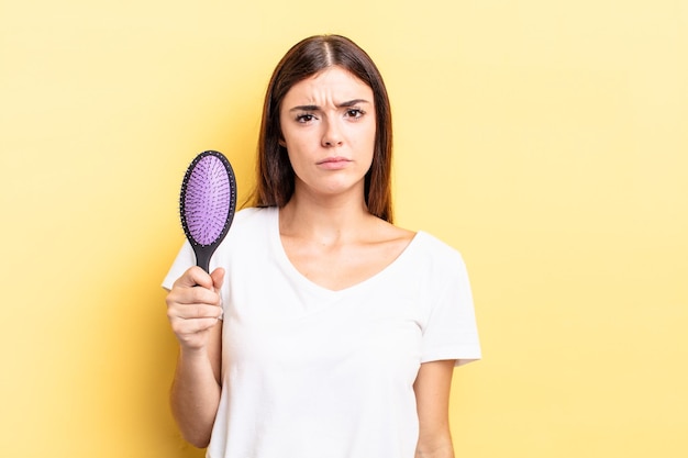 Jeune femme hispanique se sentant triste et pleurnicharde avec un regard malheureux et pleurant. concept de brosse à cheveux