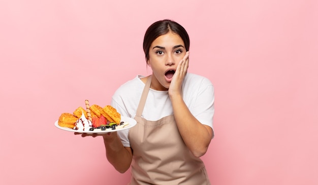 Jeune Femme Hispanique Se Sentir Choqué Et Effrayé, L'air Terrifié Avec La Bouche Ouverte Et Les Mains Sur Les Joues