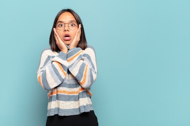 Jeune femme hispanique se sentir choqué et effrayé, l'air terrifié avec la bouche ouverte et les mains sur les joues