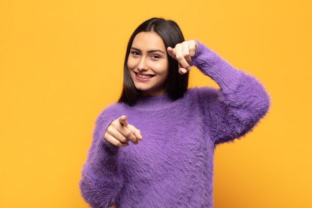 Jeune femme hispanique se sentir heureuse et confiante, pointant vers la caméra avec les deux mains et en riant, en vous choisissant