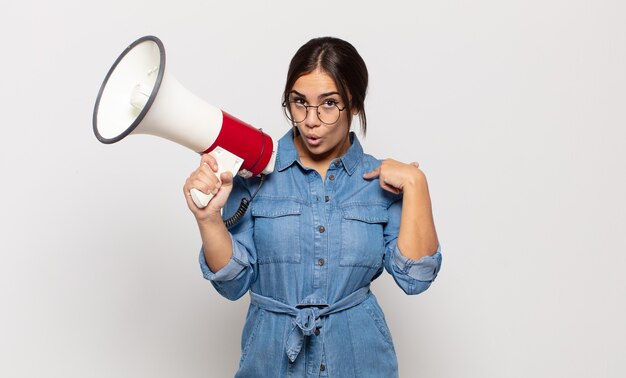 Jeune femme hispanique se sentir heureuse, surprise et fière, pointant vers soi avec un regard excité et étonné