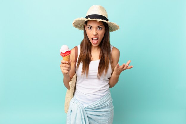 jeune femme hispanique semblant en colère, agacée et frustrée et tenant une glace. concept d'été