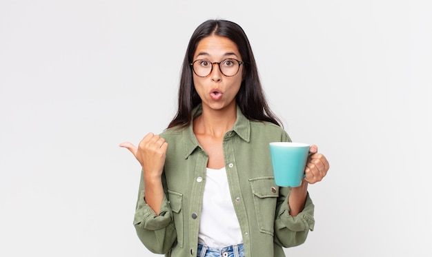 Jeune femme hispanique semblant étonnée d'incrédulité et tenant une tasse de café