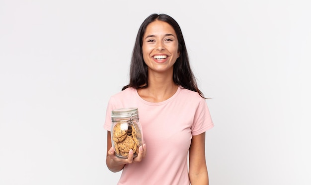 Jeune femme hispanique semblant heureuse et agréablement surprise et tenant une bouteille en verre de biscuits