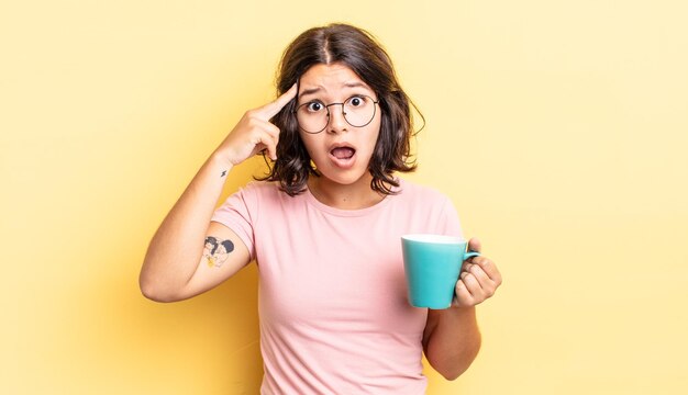 Jeune femme hispanique semblant surprise, réalisant une nouvelle pensée, idée ou concept. concept de tasse à café