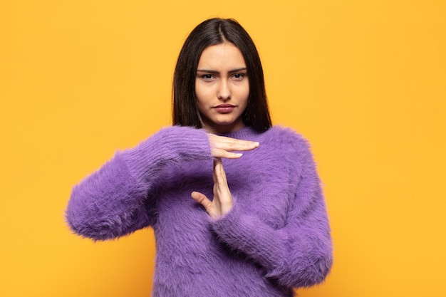 Jeune femme hispanique à la sérieuse, sévère, en colère et mécontente, faisant signe de temps