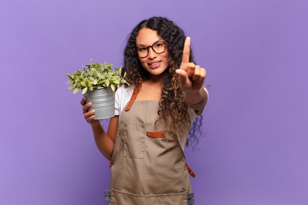 Jeune femme hispanique souriant fièrement et avec confiance, faisant la pose triomphante, se sentant comme un leader. concept de jardinier