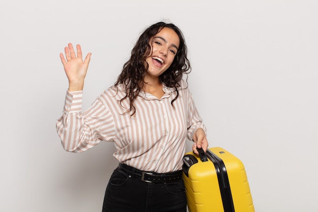 Jeune femme hispanique souriant joyeusement et gaiement, agitant la main