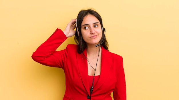 Jeune femme hispanique souriant joyeusement et rêvassant ou doutant du concept de télévendeur